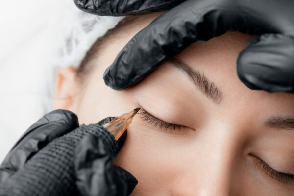 Permanent tattoo makeup on eyelashes of eyes of young woman in beauty salon.